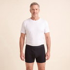 Man wearing a white T-shirt and black Cotton Classics boxer briefs on a cream background